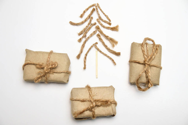 Christmas tree made of rope, jute, twine and wooden match on white background. Eco craft gift boxes. Organic DIY eco craft Christmas tree. Creative art holiday. Simple xmas backdrop. - Fotografie, Obrázek