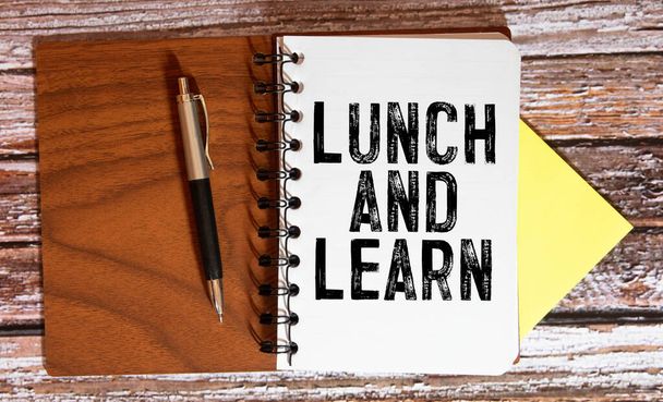 昼食と学ぶ、苦しんだ木の背景の上に昼食と学ぶという言葉を持つスパイラルメモ帳. - 写真・画像