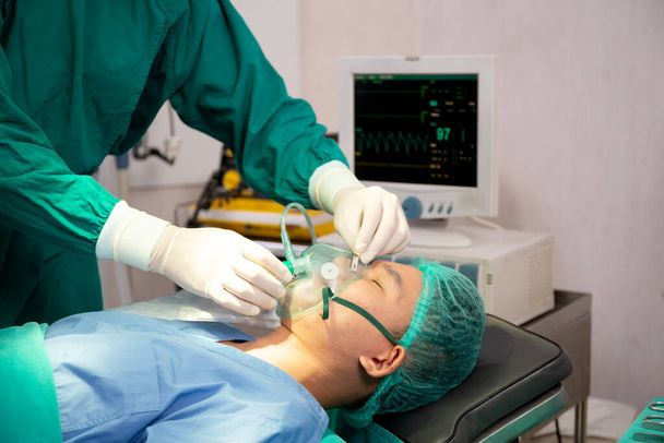 Ομάδα γιατρός και βοηθός κρατώντας μάσκα οξυγόνου με τον ασθενή έκτακτης ανάγκης στο χειρουργείο στο νοσοκομείο, χειρουργός επούλωση και χειρουργική επέμβαση, το πρόβλημα της αναπνοής, όργανα ιατρικής και υγείας. - Φωτογραφία, εικόνα
