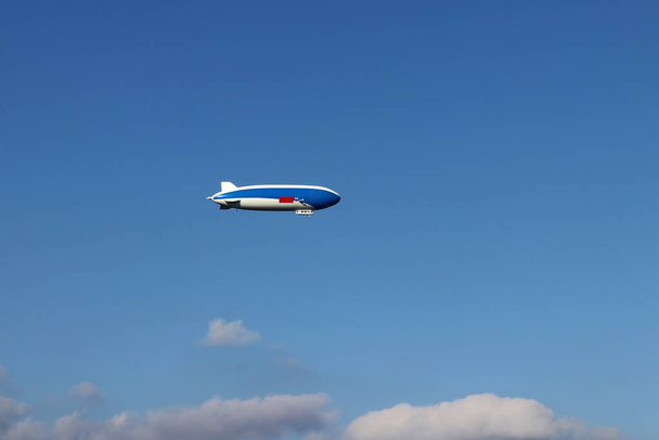 Сине-белый дирижабль летает в небе - Фото, изображение