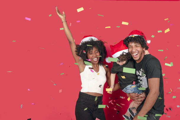 cheerful family laughing surrounded by confetti over a pink background, horizontal picture - Photo, Image