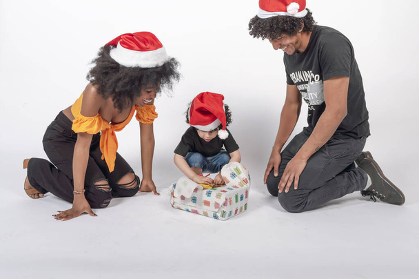 Γονατίζοντας γονείς βλέποντας το γιο τους να ανοίγει το χριστουγεννιάτικο δώρο του, οριζόντια άποψη - Φωτογραφία, εικόνα
