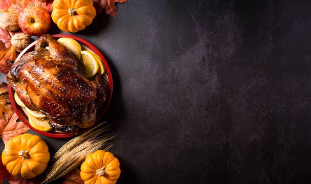 Thanksgiving dinner background concept with turkey roasted and all sides dishes, fall leaves, pumpkin and seasonal autumnal decor on dark stone background, top view, copy space. - Foto, Imagen