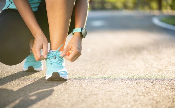 Sapatos de corrida - close-up de mulher amarrando cadarços de sapato. Feminino esporte fitness runner se preparando para correr no fundo do jardim
. - Foto, Imagem