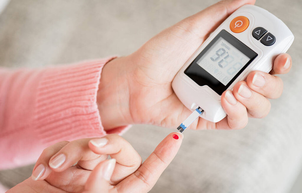 Close-up vrouw handen controleren bloedsuikerspiegel door glucosemeter voor diabetes tester met behulp van als geneesmiddel, glykemie, gezondheidszorg en medisch concept. - Foto, afbeelding