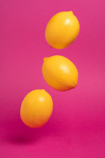Ripe lemons on bright pink paper background - Photo, Image