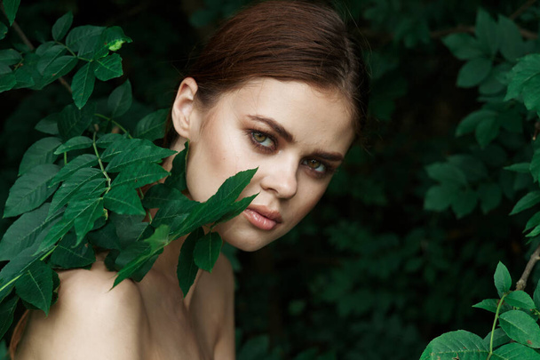 χαμογελαστή γυναίκα φροντίδα του δέρματος γυμνούς ώμους πράσινο αφήνει τη φύση close-up - Φωτογραφία, εικόνα