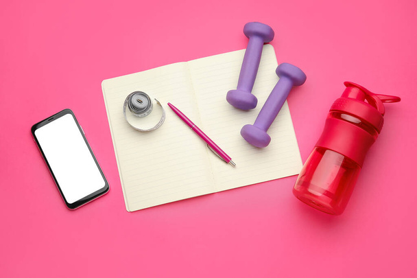 Dumbbells, notebook an mobile phone on pink background - Foto, immagini