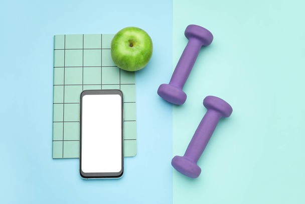 Мундштуки, мобільний телефон і яблуко на синьому фоні
 - Фото, зображення