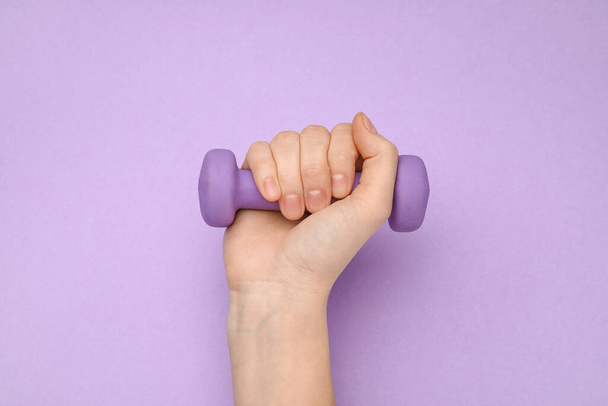 Female hand with dumbbell on purple background - Photo, Image