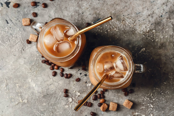 Mason jars of tasty iced coffee with milk on grunge background - Photo, Image