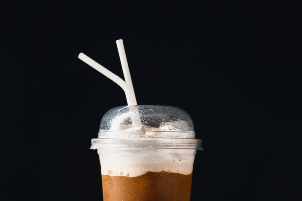 Plastový šálek chutné ledové kávy se smetanou na tmavém pozadí, detailní záběr - Fotografie, Obrázek