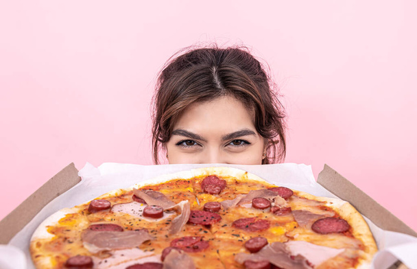 魅力的な女の子保持ピザで段ボール箱にピンクの背景. - 写真・画像
