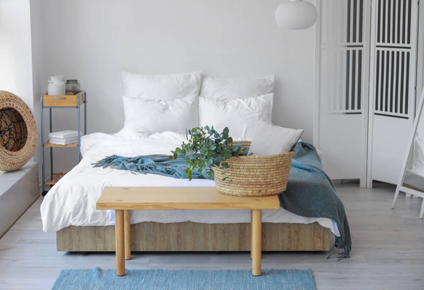 Kosz z zielonymi gałęziami eukaliptusa na ławce w sypialni - Zdjęcie, obraz
