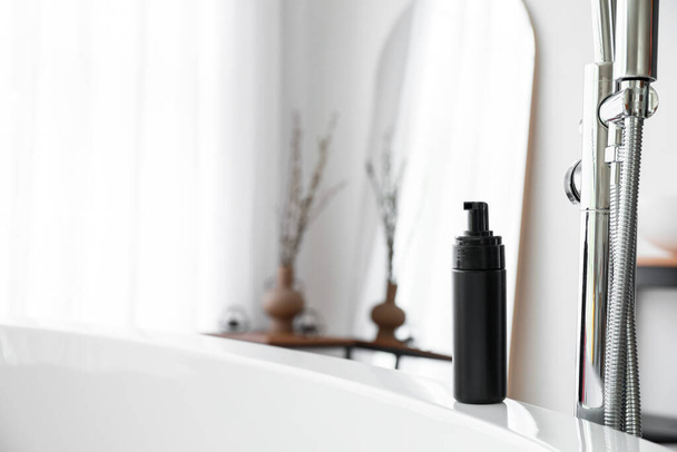 Bottle of cosmetic product on bathtub in room - Photo, Image