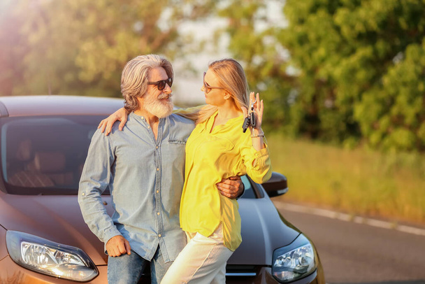 Heureux couple d'âge mûr avec des clés près de la voiture à la campagne - Photo, image