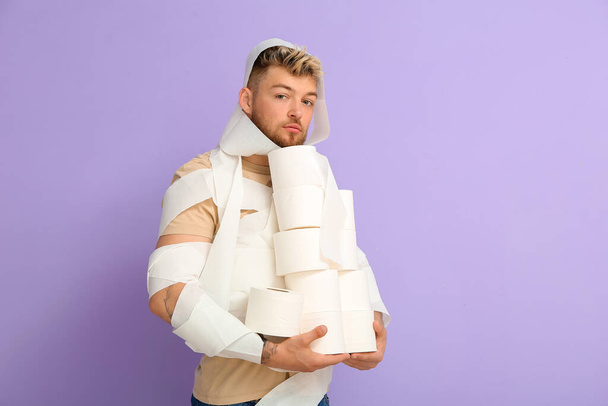 Funny young man wrapped in toilet paper on color background - Valokuva, kuva