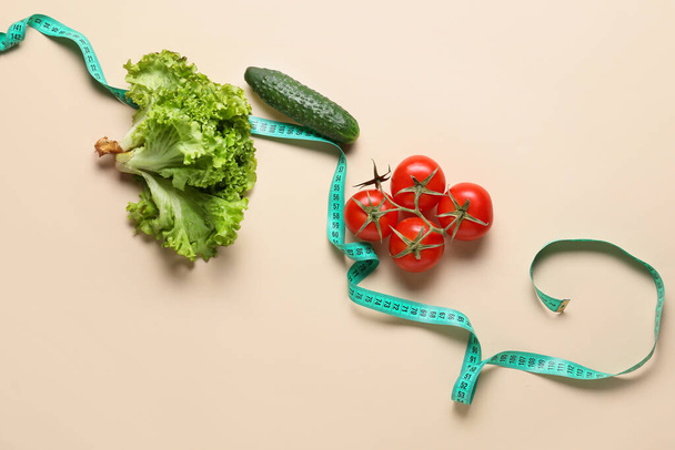 Fresh vegetables with measuring tape on beige background - Photo, Image