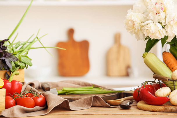 Fresh vegetables and flowers on table in kitchen - Photo, Image