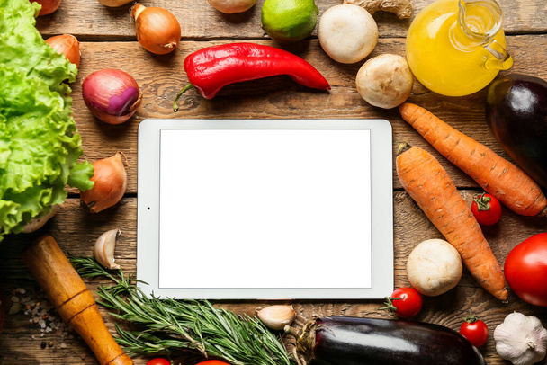 Tablet computer with tasty ingredients on wooden table - Foto, imagen