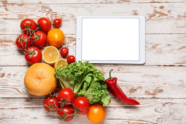 Tablet computer with blank screen and tasty ingredients on light wooden background - Photo, Image