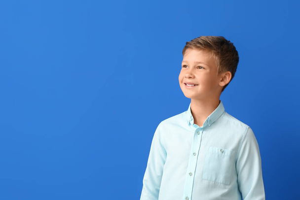 Усміхнений маленький хлопчик у сорочці на синьому фоні
 - Фото, зображення