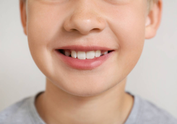 Little boy with healthy smile on light background, closeup - Photo, image
