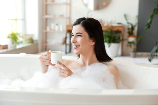 Relaxado jovem com xícara de café tomando banho em casa - Foto, Imagem
