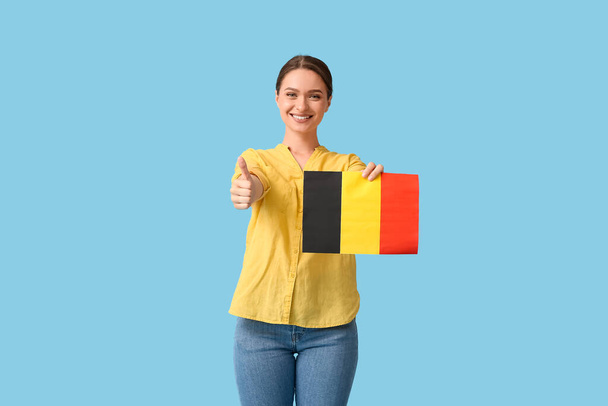 Belçika bayrağı taşıyan genç bir kadın, arka planda başparmağını kaldırıyor - Fotoğraf, Görsel