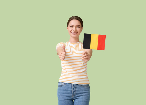 Młoda kobieta z flagą Belgii pokazuje kciuk do góry na tle koloru - Zdjęcie, obraz