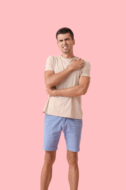 Young man scratching himself on color background - Photo, image