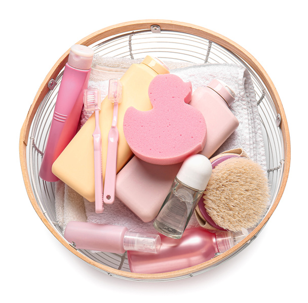 Cesta con botellas de productos cosméticos, cepillos de dientes, esponja de baño y cepillo de masaje sobre fondo blanco - Foto, imagen