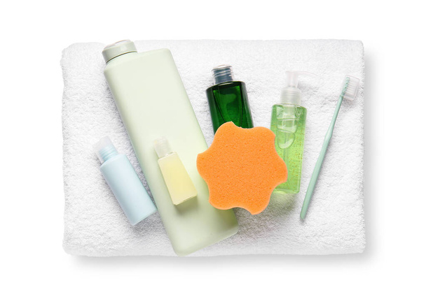 Полотенце, бутылки косметических средств, зубная щетка и губка для ванны на белом фоне - Фото, изображение