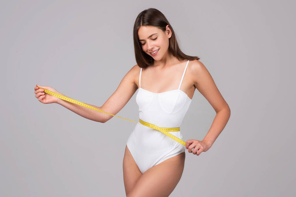 Attractive caucasian woman measuring her waist isolated background. Body care. - Фото, изображение