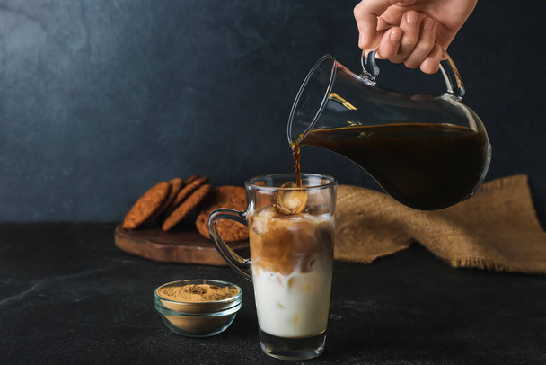 Woman preparing iced hojicha latte on black background - Fotografie, Obrázek