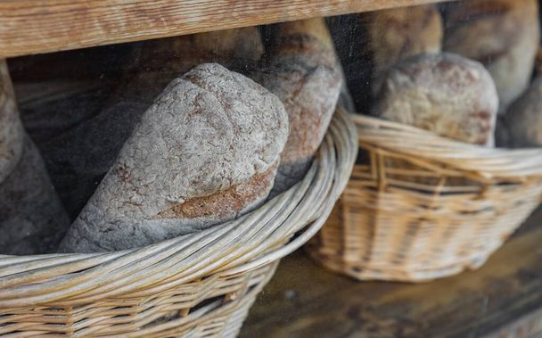 Bakery interior with glass display counters full of scrumptious bread in wicker baskets. Healthy natural rye and whole wheat bread. Street photo, selective focus, nobody - Photo, Image