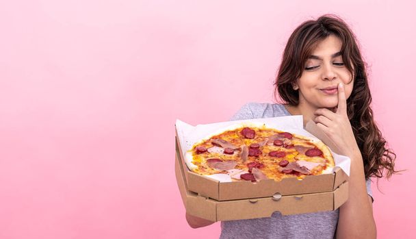 魅力的な女の子とともにピザでボックス上の配達のためにピンクの背景. - 写真・画像