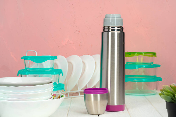 Thermos bottle against tableware in a kitchen - Photo, image