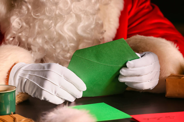 Kerstman leest brief aan tafel op kerstavond - Foto, afbeelding