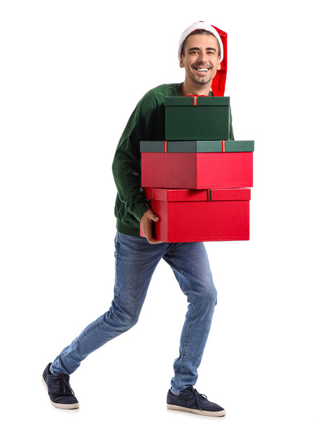 Young man in Santa hat with Christmas presents on white background - Foto, imagen