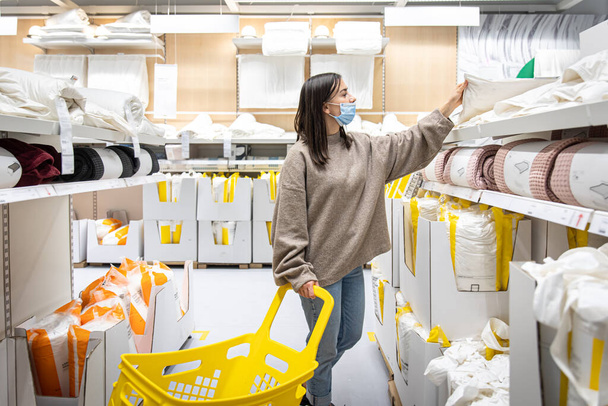 Jonge vrouw met een gele trolley in een winkel met huishoudelijke artikelen. - Foto, afbeelding