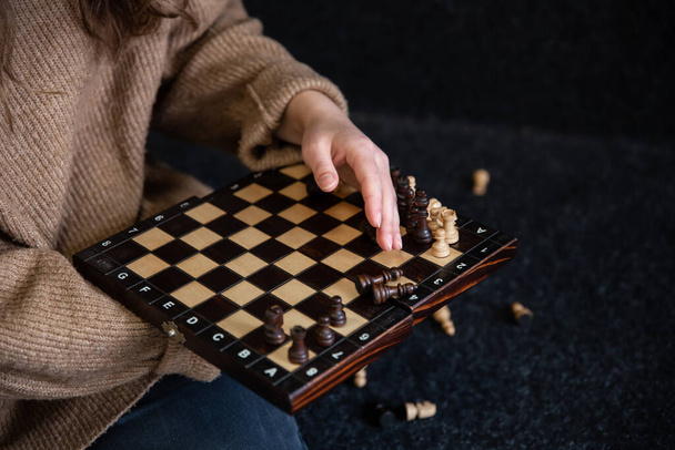Chess board with wooden chess pieces in female hands. - Photo, Image
