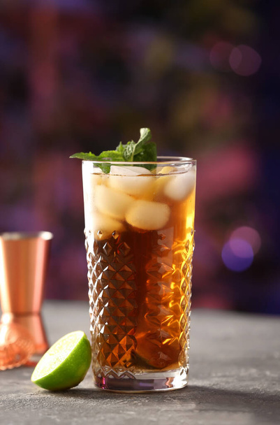 Verre de savoureux Cuba Libre cocktail avec menthe sur la table dans le bar - Photo, image