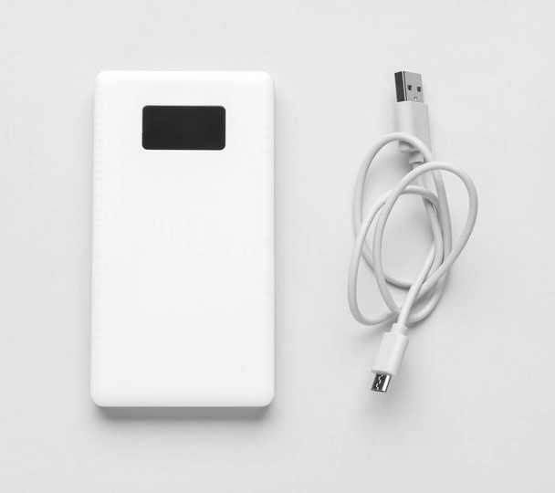 Modern power bank and USB cable on light background - Photo, Image