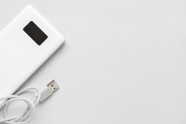 Modern power bank and USB cable on light background, closeup - Photo, Image