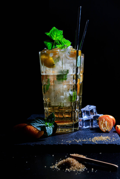 duas bebidas coloridas de verão com hortelã e kumquat em uma mesa preta. deitado plano - Foto, Imagem