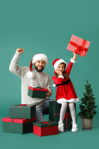 Little girl and her father with Christmas tree and gifts on color background - Foto, afbeelding