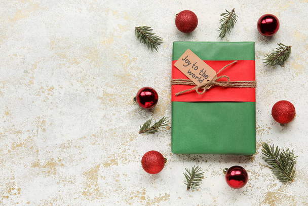 Frame gemaakt van dennenboomtakken, kerstballen, geschenkdoos en -kaart met tekst JOY TO THE WORLD op lichte ondergrond - Foto, afbeelding