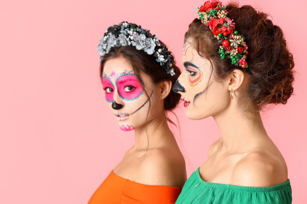 Tyylikkäät naiset, joilla on maalattu kallo kasvoilla väritaustaa vasten. Meksikon kuolleiden päivän juhla (El Dia de Muertos) - Valokuva, kuva