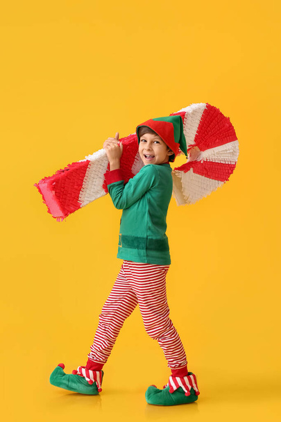 Cute little boy dressed as elf with candy cane pinata on color background - Foto, immagini